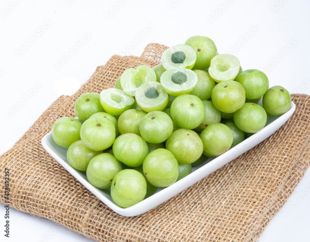 Indian gooseberry fruits or Amla berry ( phyllanthus emblica ) and sliced in white palte on white background. Indian gooseberry fruits or Amla berry ( phyllanthus emblica ) and sliced in white palte on white background.