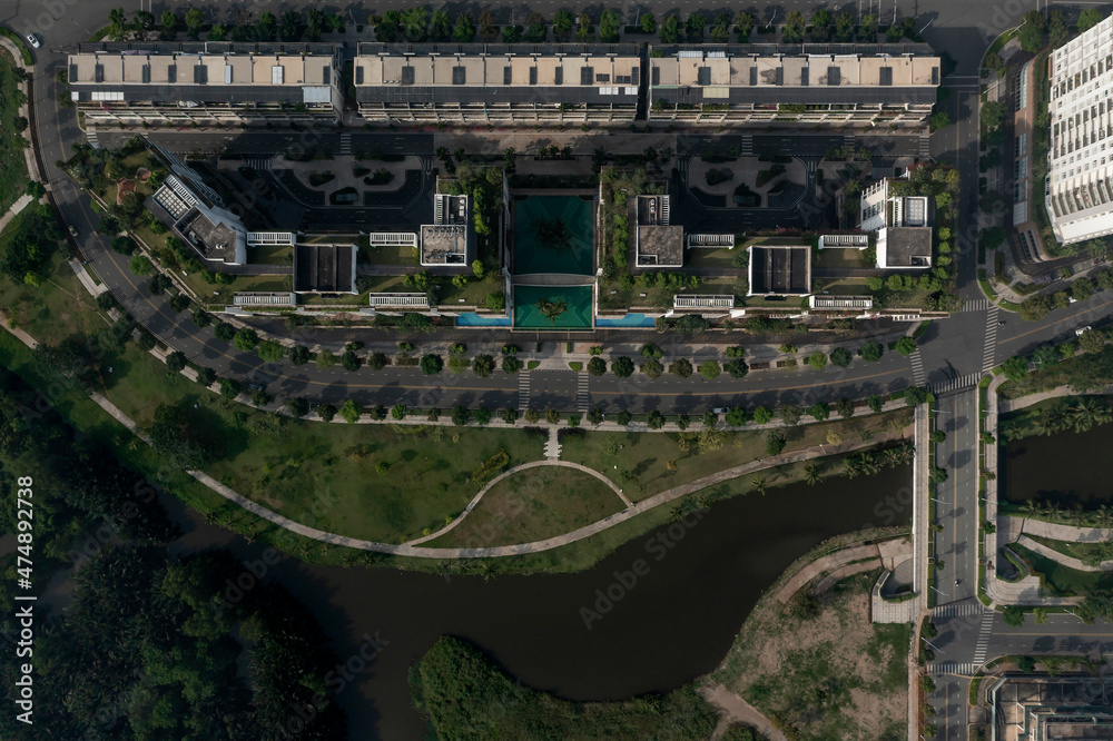 Top down aerial view of ultra modern lakeside housing and apartment development on a sunny day with park, green space, bridge and new architecture.