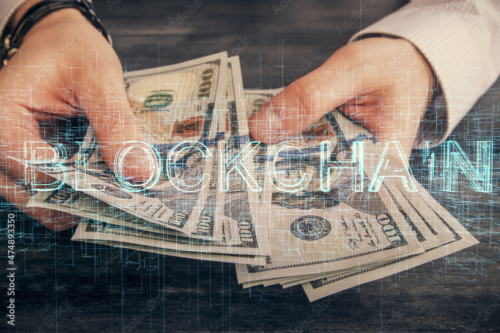 Multi exposure of blockchain theme drawing hologram and USA dollars bills and man hands. Business concept.