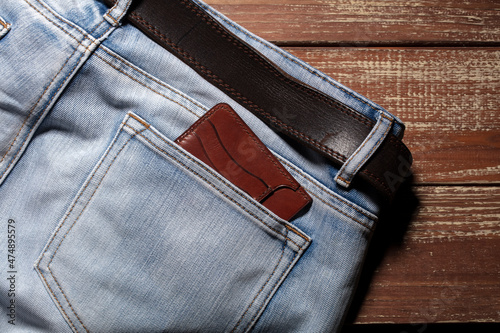 Wallet from the back pocket of jeans on a wooden background.