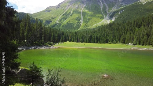 Beach with green colored water of the Obernberger Lake in Tyrol (Austria), with mountains and a forest in the background photo