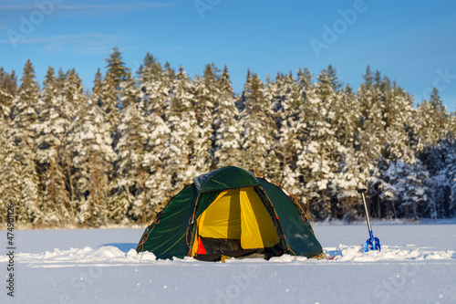 Green tent in snowy winter forest. Background blurred.