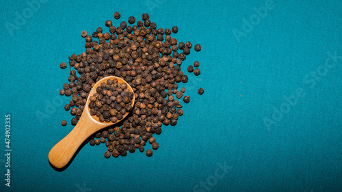 Tas de poivre noir en grain avec cuillère en bois photo