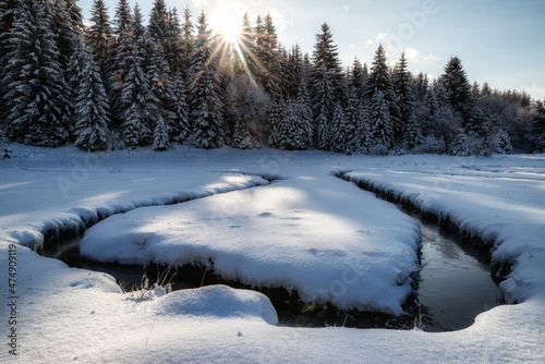 Meandering of the flow of the mountain stream in snowy winter country. Liptovska Luzna, Slovakia photo