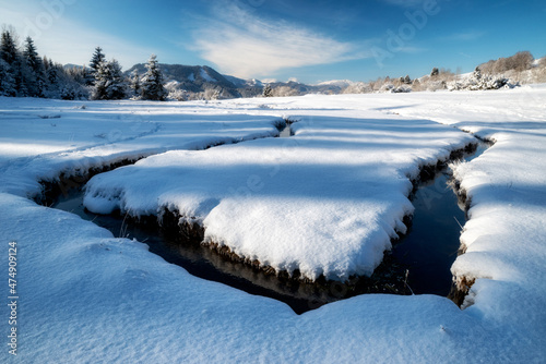 Meandering of the flow of the mountain stream in snowy winter country. Liptovska Luzna, Slovakia