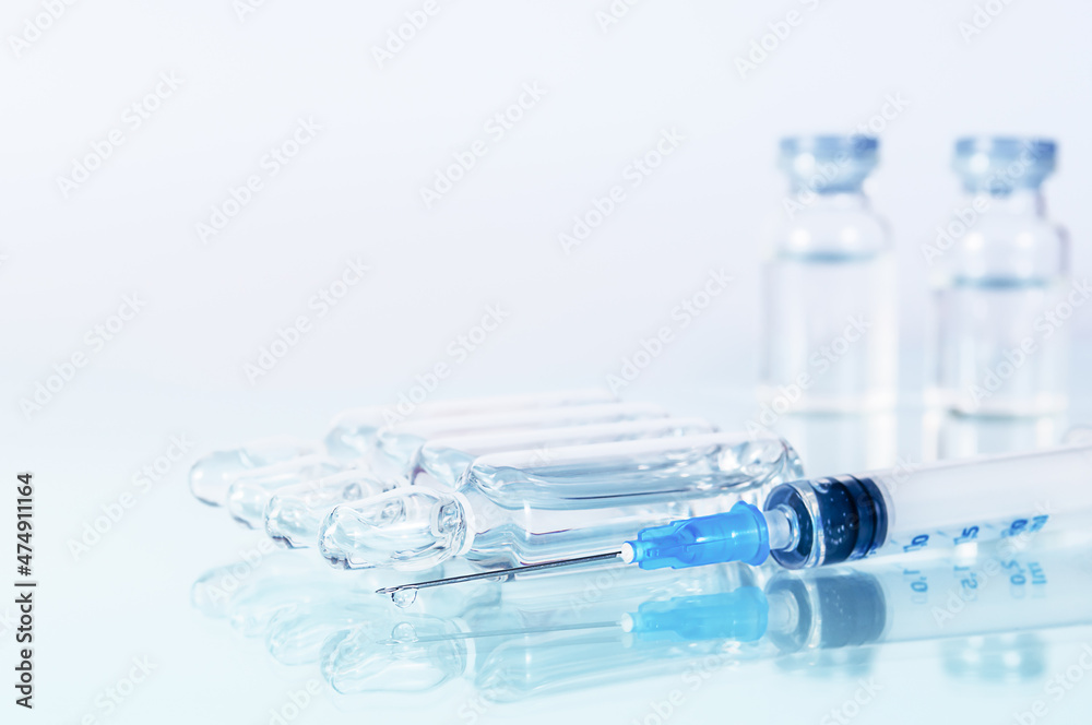 syringe and diferent kind of ampoules and vials close-up on white background with reflection syringe and diferent kind of ampoules and vials close-up on white background with reflection