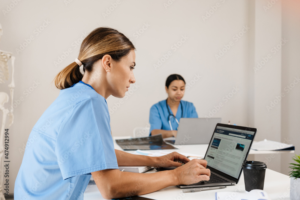 Multiracial women doctors working with laptops in office