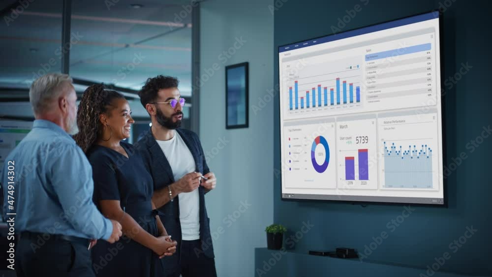 Company Operations Manager Holds Meeting Presentation for a Team of Economists. Adult Male Uses TV Screen with Growth Analysis, Charts, Statistics and Revenue. People Work in Business Office.