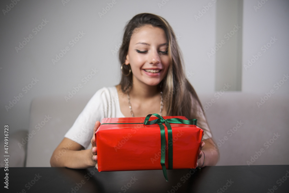 smiling woman holding red wrapped gift wrap , indoor photo smiling woman holding red wrapped gift wrap , indoor photo