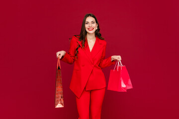 attractive woman in red with shopping bags sale on red background