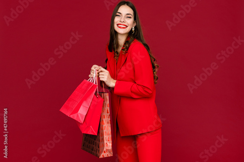 attractive woman in red with shopping bags sale on red background