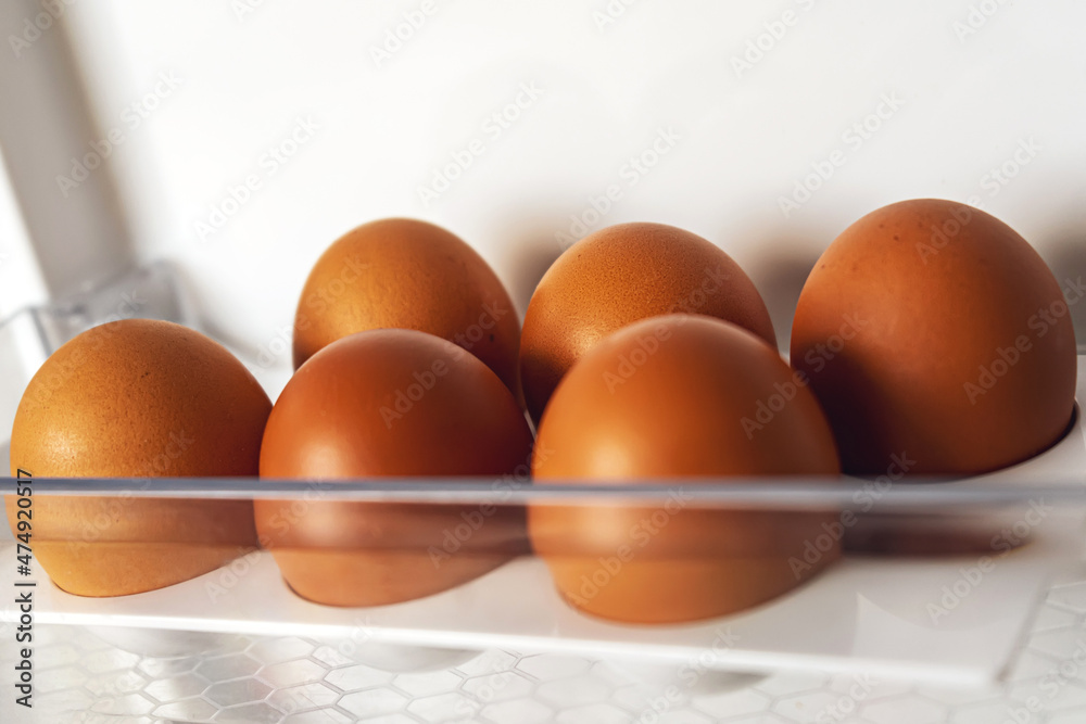 half dozen eggs in the refrigerator tray. 6 brown chicken eggs in an empty colloquially fridge. half dozen eggs in the refrigerator tray. 6 brown chicken eggs in an empty colloquially fridge.