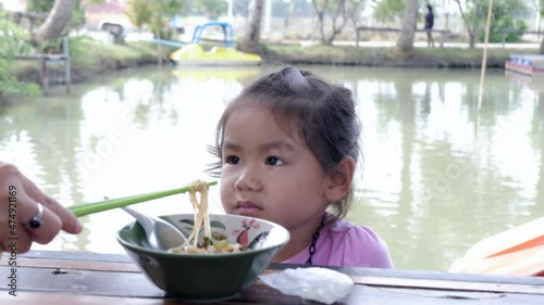 Slow motion scene of 5-year-old Asian girl sits and loses her appetite refuse to eat noodles