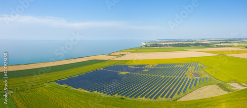 The panoramic view of Norman solar panels in the flax fields in Europe, France, Normandy, in summer on a sunny day.