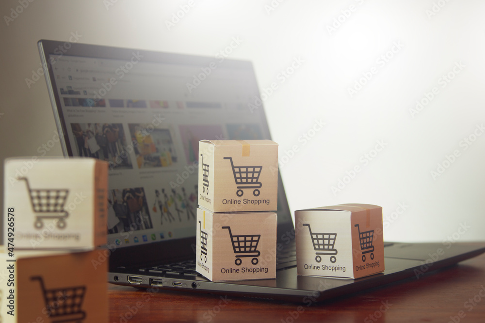 Obraz premium Online shopping/ecommerce and shipping concepts: A cardboard box with a cart or cart logo on a laptop keyboard represents a customer placing an order from a retail store over the Internet.