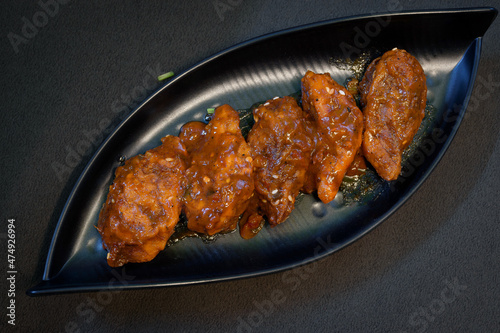 Chicken stuffed pan fried momo, a popular food in India, served on a black plate on a black background.