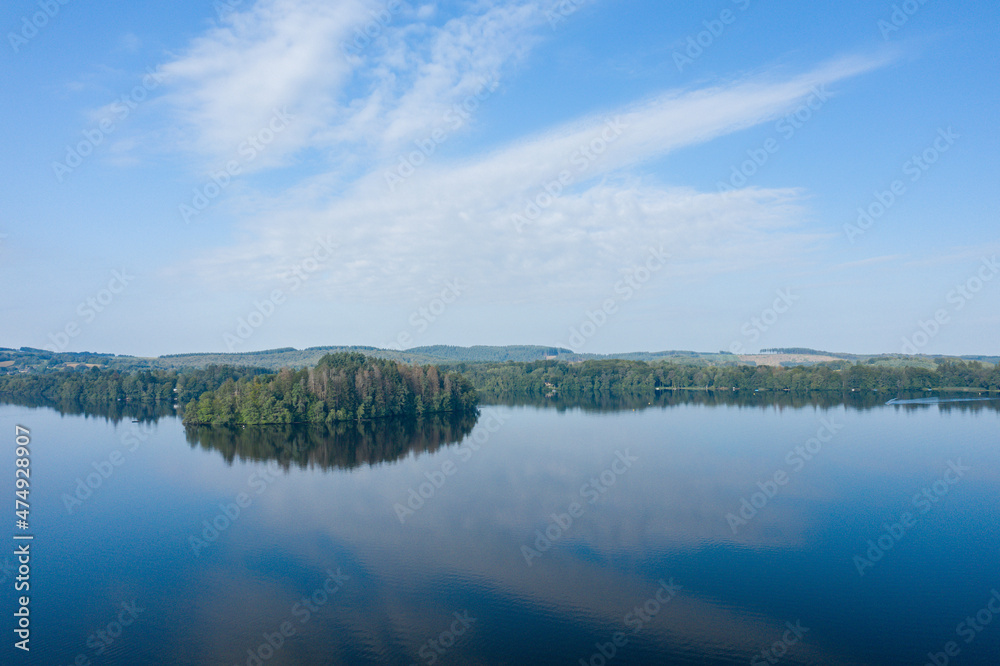 a green island in the middle of the Lac des Settons in Europe, France, Burgundy, Nievre, Morvan, in summer, on a sunny day.