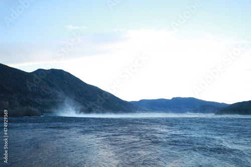 Mountain river and mountains in Norway. Strong wind on the water. Breeze from the wind. The beauty of Norwegian nature. Bank of the river. Coniferous pine trees on the banks of a river in Norway high  © Hanna Ohnivenko