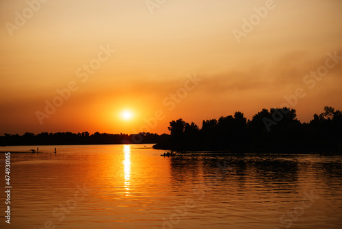 orange sunset on the river with silhouettes © omelnickiy