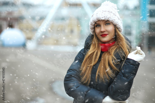 Stylish blond lady walking at the city with snowflakes