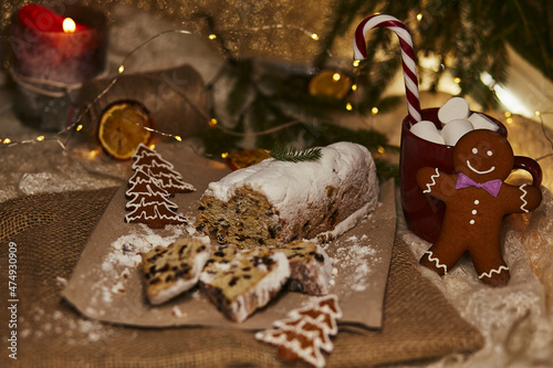 Seasonal Christmas stollen, gingerbread cookies, hot beverage with marshmallow, Christmas Candy Cane and Christmas decorations. Christmas tradition with festive bokeh background. photo