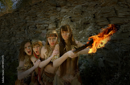 Four girls are dressed as Neanderthal warriors. Their 
faces are filled with anger and are seen waving a 
blazing torch in a stone quarry