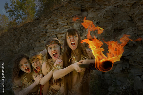 Four girls are dressed as Neanderthal warriors. Their 
faces are filled with anger and are seen waving a 
blazing torch in a stone quarry