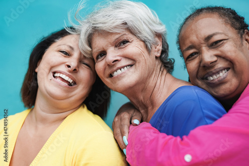 Multiracial senior women hugging together while smiling on camera