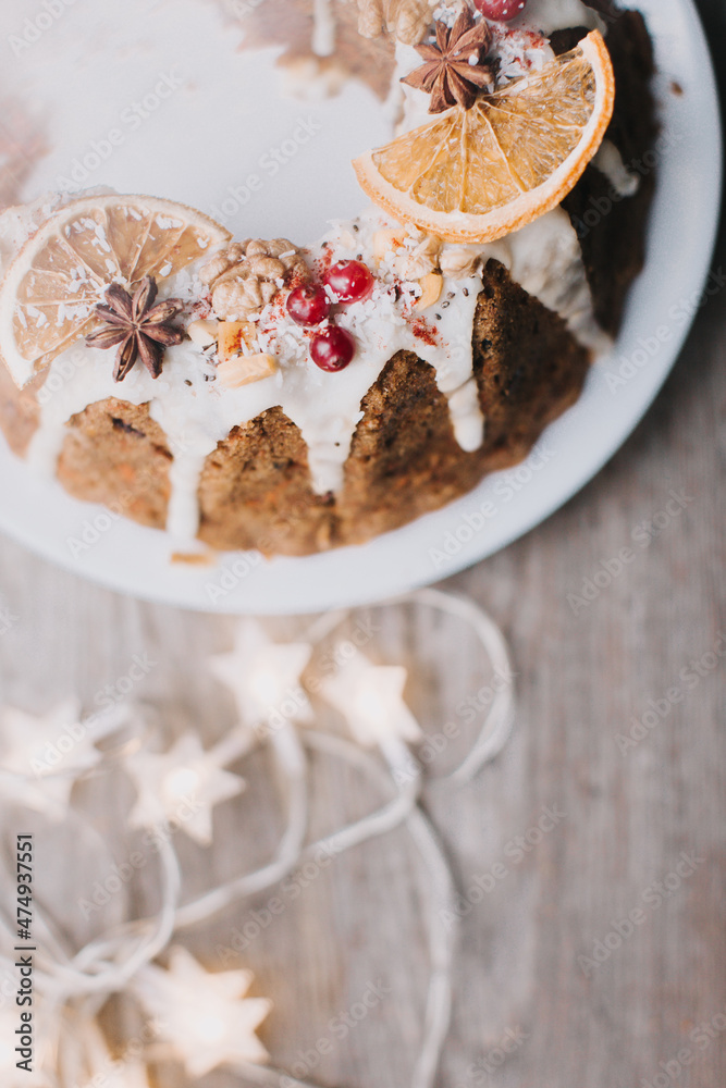 Traditional Christmas fruit cake decorated with glaze, orange, cranberries and nuts on the table Traditional Christmas fruit cake decorated with glaze, orange, cranberries and nuts on the table