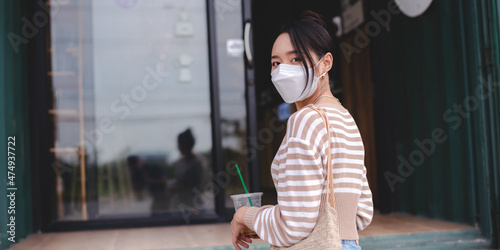 young Asian woman wearing surgical face mask for a new normal lifestyle living in city urban