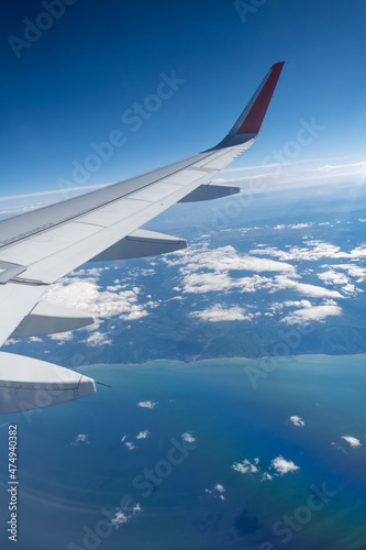 Classic image through aircraft window onto wing. Flight view over sea in cloudy weather