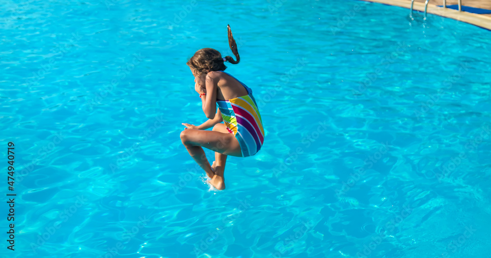 The child jumps dives into the pool. Selective focus.