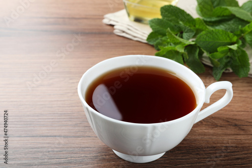 Cup of hot aromatic tea with mint on wooden table
