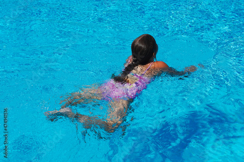 Little girl at swimming pool. Smiling Girl having fun in swimming pool on summer vacation. Swimming girl.