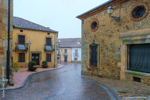 Alley of old houses in a picturesque medieval village in foggy day. Riaza Segovia. photo