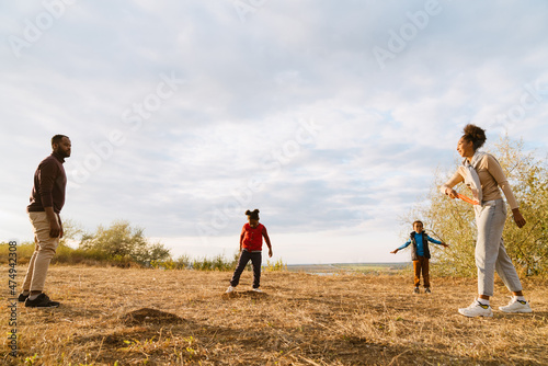 Black family laughing and playing with frisbee during walking