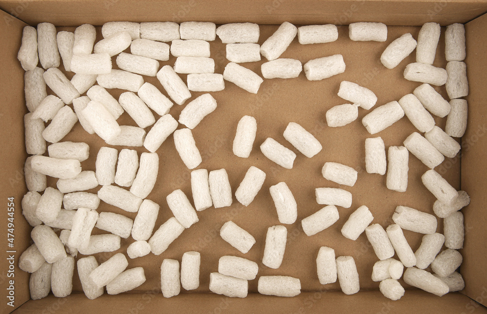 Styrofoam packing peanuts in cardboard box background. White plastic foam pellets protective for parcel packing. Styrofoam packing peanuts in cardboard box background. White plastic foam pellets protective for parcel packing.