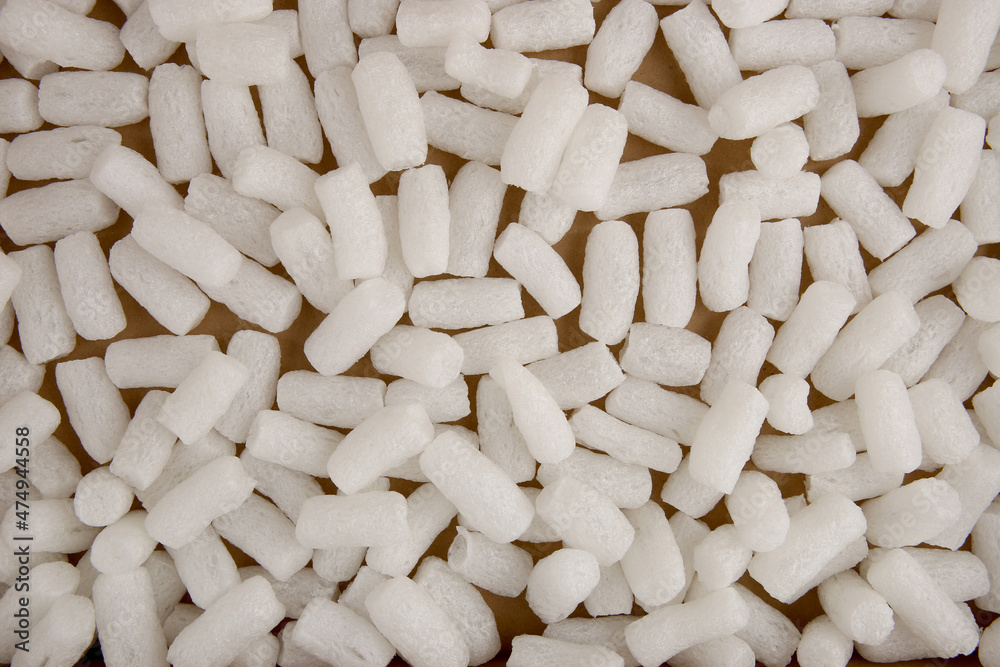 Styrofoam packing peanuts in cardboard box background. White plastic foam pellets protective for