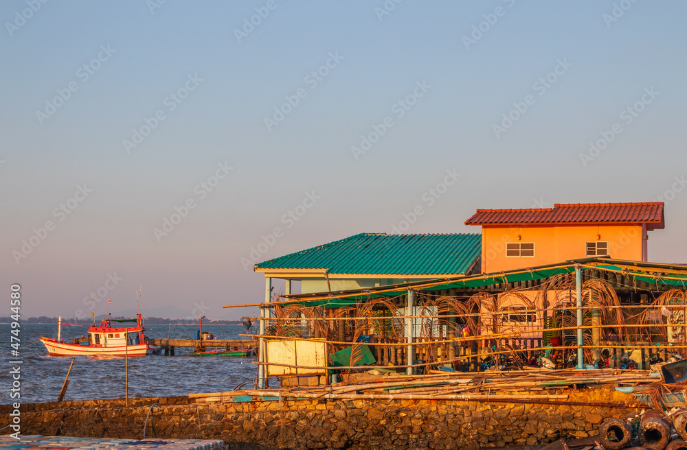Obraz premium A fishing boat and a house building right on the coastline at the time of the late afternoon