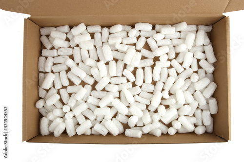 Styrofoam packing peanuts in cardboard box isolated in on white background. White plastic foam pellets protective for parcel packing.