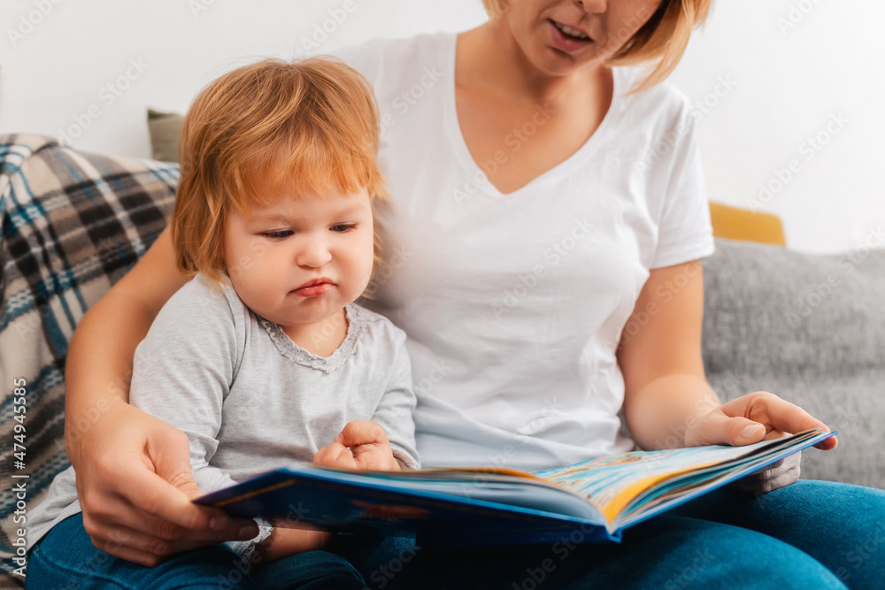 Speech therapist is reading a book to bored child sitting on the sofa. Preschool education Speech therapist is reading a book to bored child sitting on the sofa. Preschool education