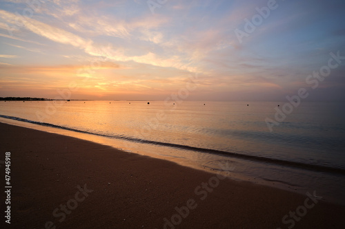 Calm sea shore with crushing waves on sandy beach at sunrise