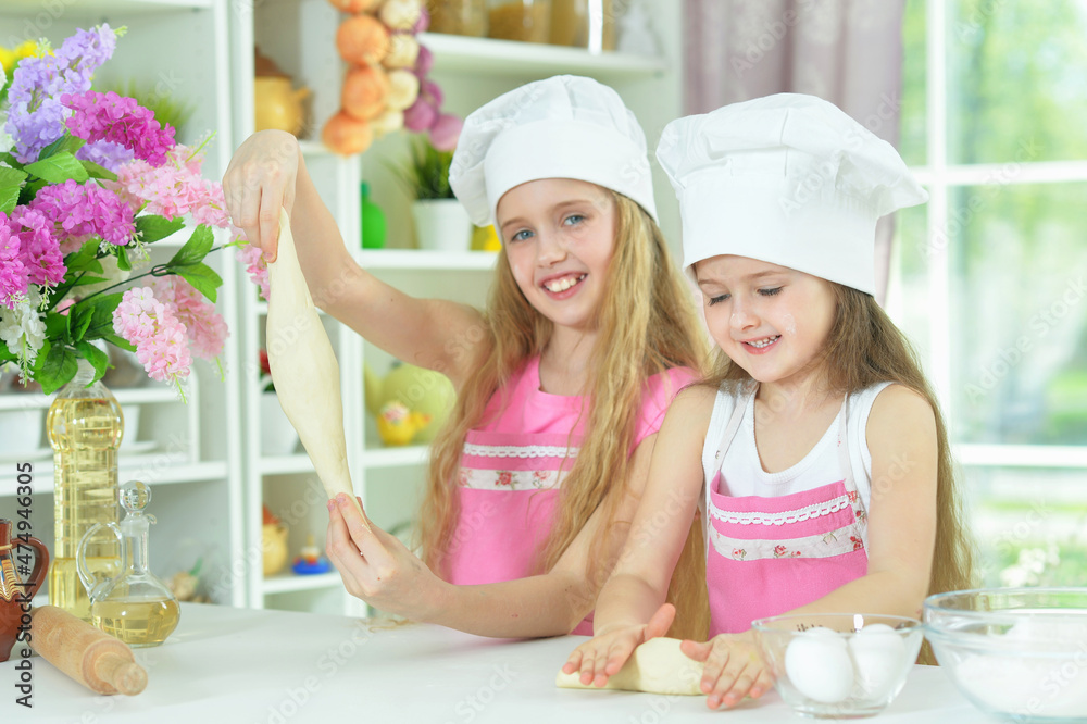 Cute little girls in chefs hats making dough Cute little girls in chefs hats making dough