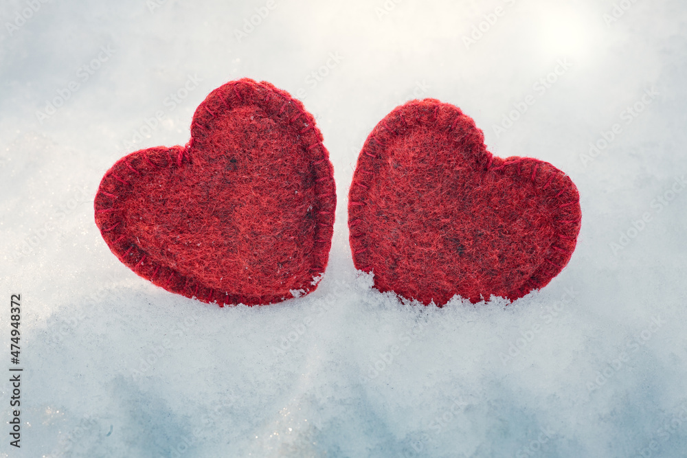 Obraz premium two red woolen hearts on the snow in winter, Valentine's Day decoration, 14 February background