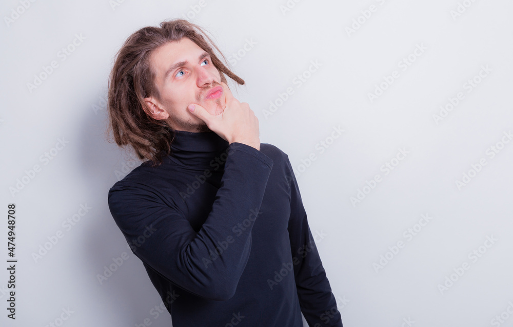 Portrait of a funny man thinking on something in dark gray turtleneck and short dreadlocks on head isolated on gray background copy space Portrait of a funny man thinking on something in dark gray turtleneck and short dreadlocks on head isolated on gray background copy space