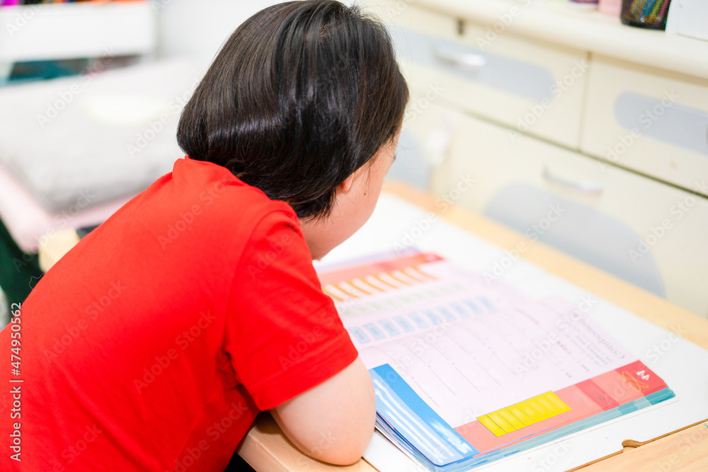 Naklejka premium Child sit and read book on table in room house