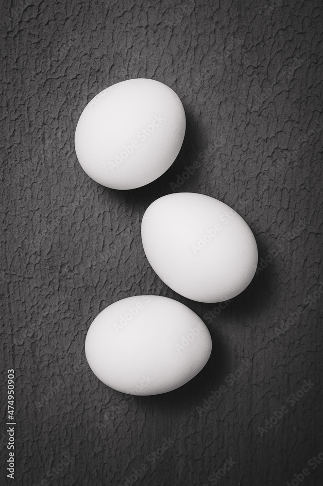 three chicken eggs on a textured surface - black and white photo three chicken eggs on a textured surface - black and white photo