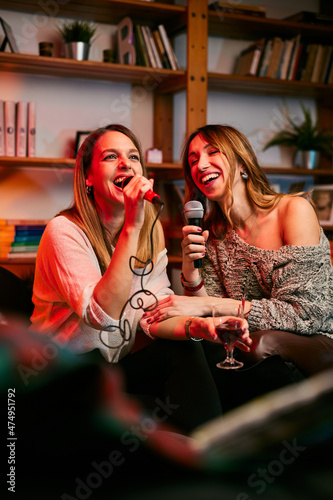 Talented girls with beautiful voices sit at home and sing a duet at karaoke night.