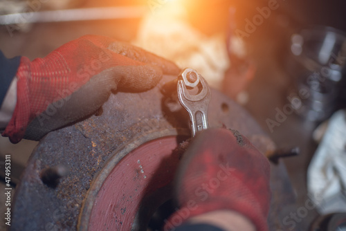 A locksmith unscrews the nut from the stud with a wrench on a rusty iron piece. © Sviatoslav Khomiakov