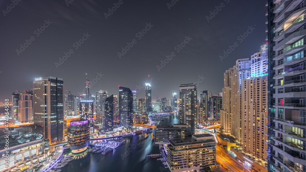 Naklejka premium Aerial view to Dubai marina skyscrapers around canal with floating boats all night timelapse